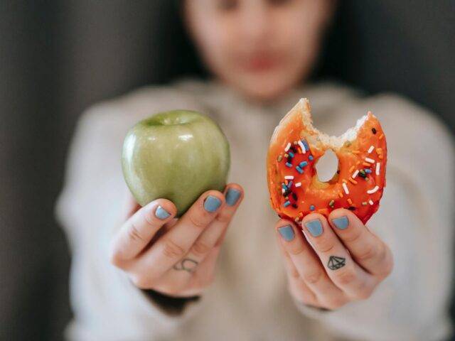 Ragazza indecisa se mangiare una mela o una ciambella di rimedi cerca rimedi efficaci per combattere la fame nervosa